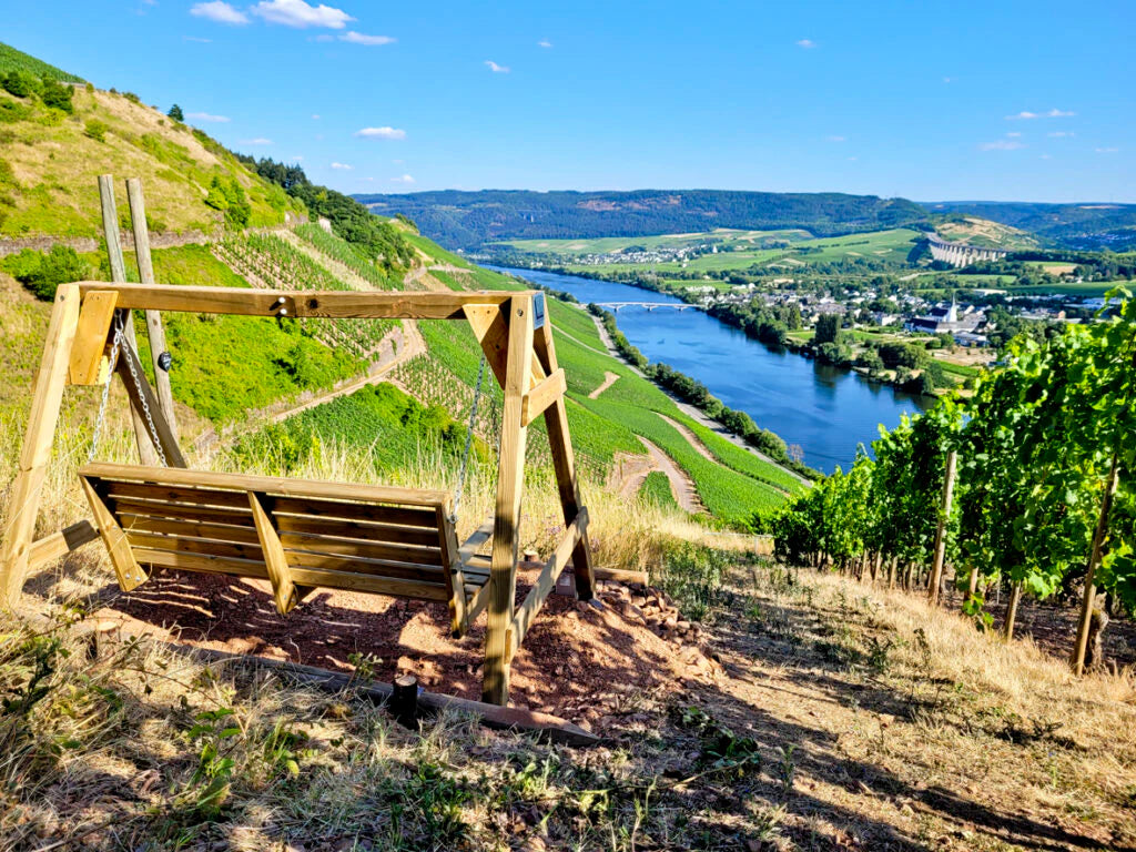 Holzschaukel mit Blick über die steilen Weinberge von Schweich an der Mosel, Panorama auf das Moseltal mit Fluss, Weinlagen und Ortschaft – beliebter Aussichtspunkt des Weinguts Günter Gindorf.